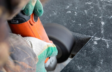 Grinding marble with a grinder. A woman's hand in a cloth, protective gloves holds the grinder. Grinding marble with a grinder. The manufacture of the monument.