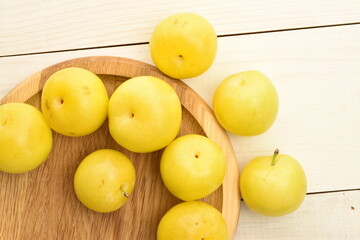 Ripe yellow plum, close-up, on a white wooden table.