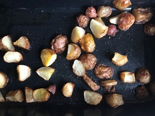 Top view of delicious Serbian baked potatoes on black baker dish 