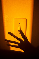 Sombra de mão apagando a luz em um interruptor na parede