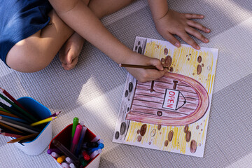 the child draws with pencils on a piece of paper, pitchfork on top
