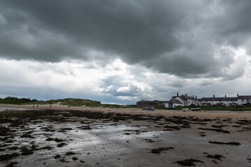The tide has turned at Low Newton-by-the-Sea but clouds are heavy before the rain on a warm summers day.