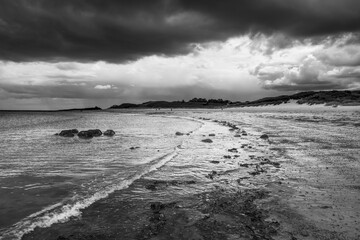 The tide has turned at Low Newton-by-the-Sea but clouds are heavy before the rain on a warm summers day.