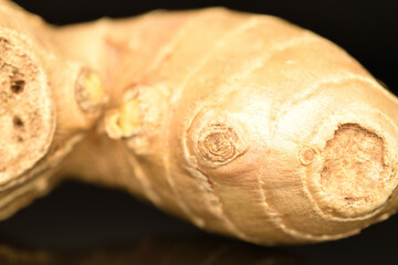 Ripe ginger root, close-up, on a black background.