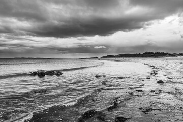 The tide has turned at Low Newton-by-the-Sea but clouds are heavy before the rain on a warm summers day.
