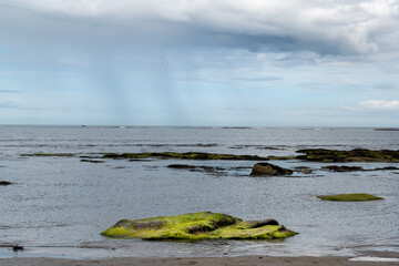 The tide has turned at Low Newton-by-the-Sea but clouds are heavy before the rain on a warm summers day.