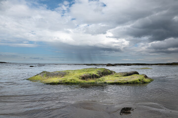The tide has turned at Low Newton-by-the-Sea but clouds are heavy before the rain on a warm summers day.