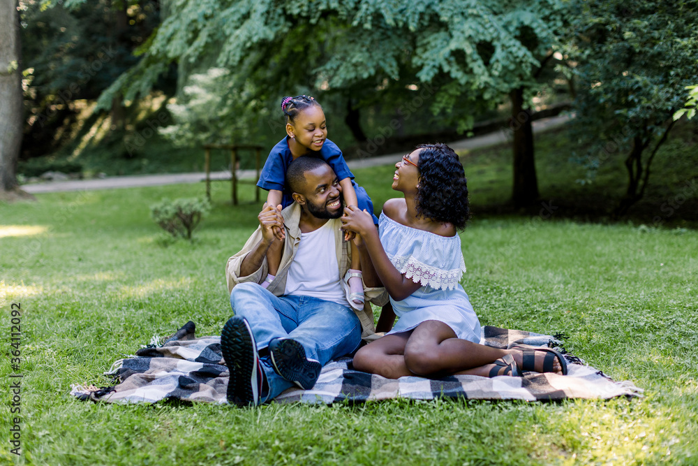 Wall mural happy african family of three having picnic in park on summer day. young family outdoors in a park, 