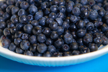 Spoon juicy blueberries in a white bowl