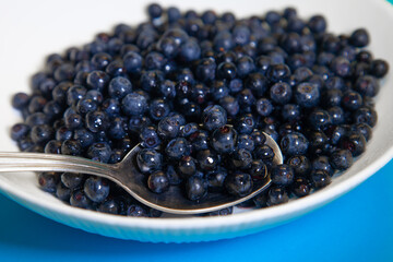 Spoon juicy blueberries in a white bowl