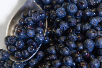 Spoon juicy blueberries in a white bowl