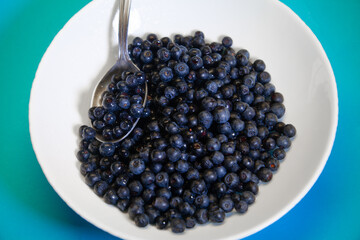 Spoon juicy blueberries in a white bowl
