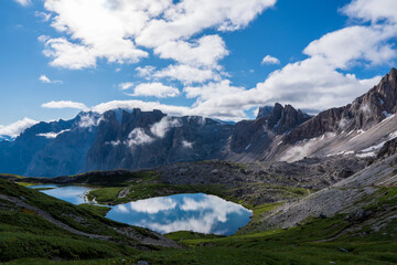 Naklejka na ściany i meble Dolomites Alps. Lago dei Piani. Italy. Two alpine lakes on background of dolomite grey peak Crode dei Piani mountain wrapped by white clouds. Desert view
