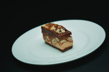 brownie cake piece with peanuts on white plate