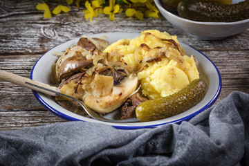 Fried liver with onion and apple, served with boiled potatoes and pickled cucumber.