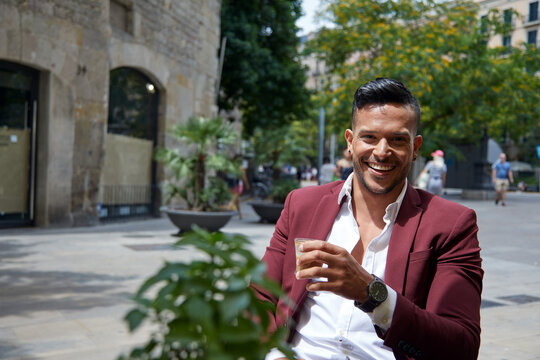 Hombre joven tomando cafe en terraza con traje rojo en Barcelona