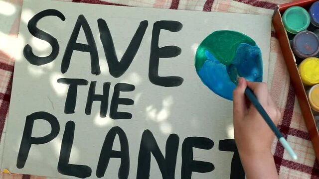 young kids drawing Save the planet Poster in summer camp. volunteer child painting earth banner. people protest against global warming, pollution, recycle. World Ecology Day, environmental problem
