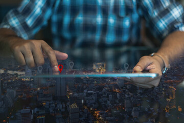 GPS map, pin address location on mobile apps. Double exposure of man hand using digital tablet searching target place on night cityscape while working in office.