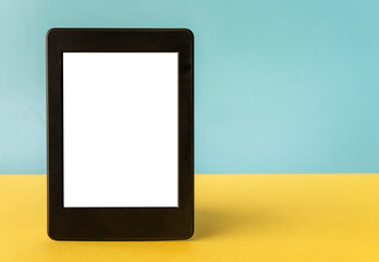 A modern black electronic book with a white blank empty screen on yellow and blue background with empty space