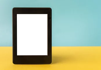 Ein modernes schwarzes elektronisches Buch mit einem weißen, leeren Bildschirm auf gelbem und blauem Hintergrund mit leerem Raum © kemaltaner
