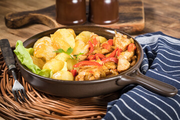 Fried pieces of chicken with red peppers and onions.