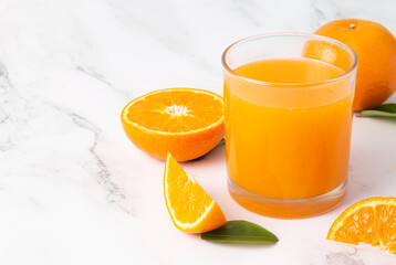 Fresh orange juice in glass and oranges fruit on white marble table background with copy space.