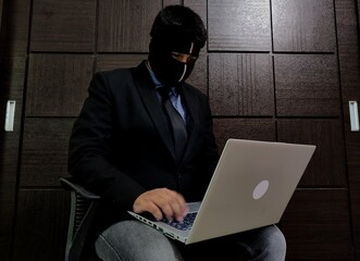 A young man wearing mask and is working on a laptop