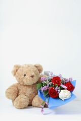 Brown teddy bear with bouquet of roses beautiful on white wood, white background. Copy space concept valentines day.