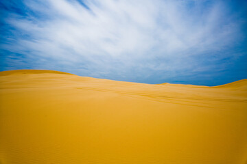 Fototapeta na wymiar 고요한 사막의 모래 언덕과 파란 하늘 속 구름