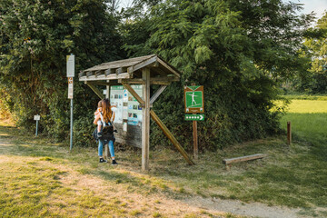 Torbiere del Sebino nature reserve. Mom with daughter looking at park signs