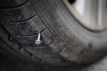 Close up button head needle metal nail stuck to puncture into wheel tire - Powered by Adobe