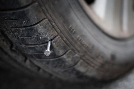 Close up button head needle metal nail stuck to puncture into wheel tire