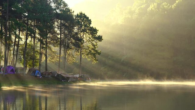Camping in nature lake with fog floating on lake and sunlight beam morning at Mae Hong Son, Thailand