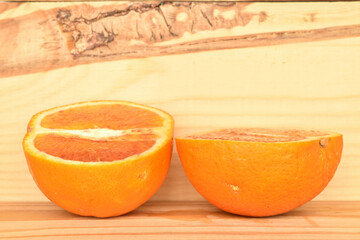 Juicy organic oranges, close-up, on a natural wood background.