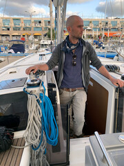 A skipper stands on a yacht before sailing in the sea