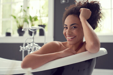 Cheerful young woman starting day with hot bath