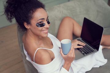 Merry young woman relaxing with gadget at home
