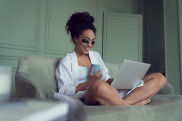 Cheerful woman relaxing with laptop at home