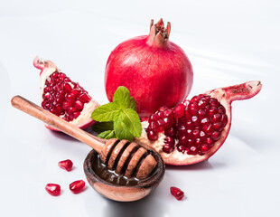 Rosh Hashanah Jewish holiday concept - red pomegranate and two slices, honey in wooden saucer with...