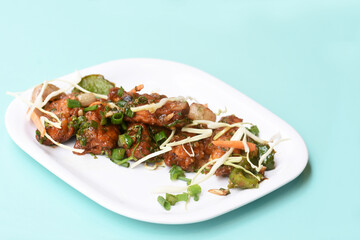 Chilli paneer or Spicy cottage cheese, Garnish with capsicum, onion,cabbage and spring onion, favourite indian starter menu, served in white Dish,selective focus