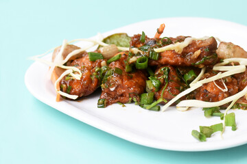 Chilli paneer or Spicy cottage cheese, Garnish with capsicum, onion,cabbage and spring onion, favourite indian starter menu, served in white Dish,selective focus