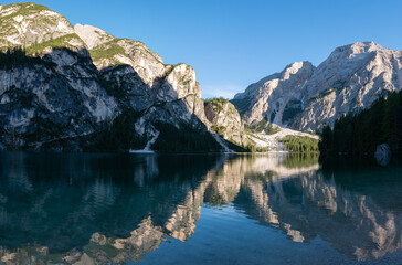 Fototapeta na wymiar Braies Lake in Dolomites mountains forest trail in background, Sudtirol, Italy. Lake Braies is also known as Lago di Braies. The lake is surrounded by forest which are famous for scenic hiking trails.