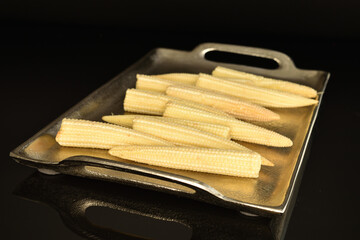 Ripe sweet ears of mini corn, close-up, isolated on black.