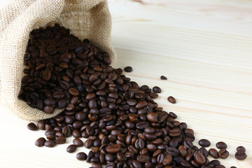 Coffee beans in a bag sack on wooden table with copy space background.