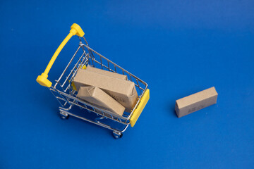 Yellow shopping cart or trolley and small , Product box, Package box , Isolated on blue background .Shopping symbols in shopping malls and general business concept.