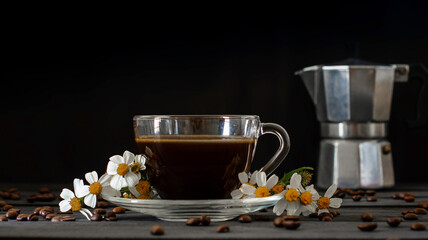 Hot coffee in a coffee cup and roasted coffee beans with flowers beside the cup on a dark tone wood floor. And there is a copy space. There is a blurry background to a coffee pot.