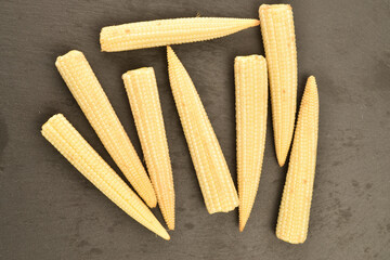 Sweet ripe mini corn, close-up, on a slate board.