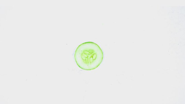 Stop motion of sliced fresh green cucumber moving and spreading on the table in the studio, isolated on white background