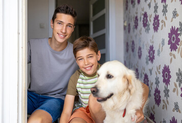 Two boys with a dog in doorway of their house
