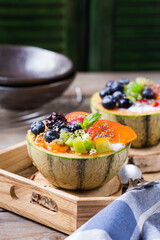 Fruit salad with yogurt in carved melon cantaloupe bowl